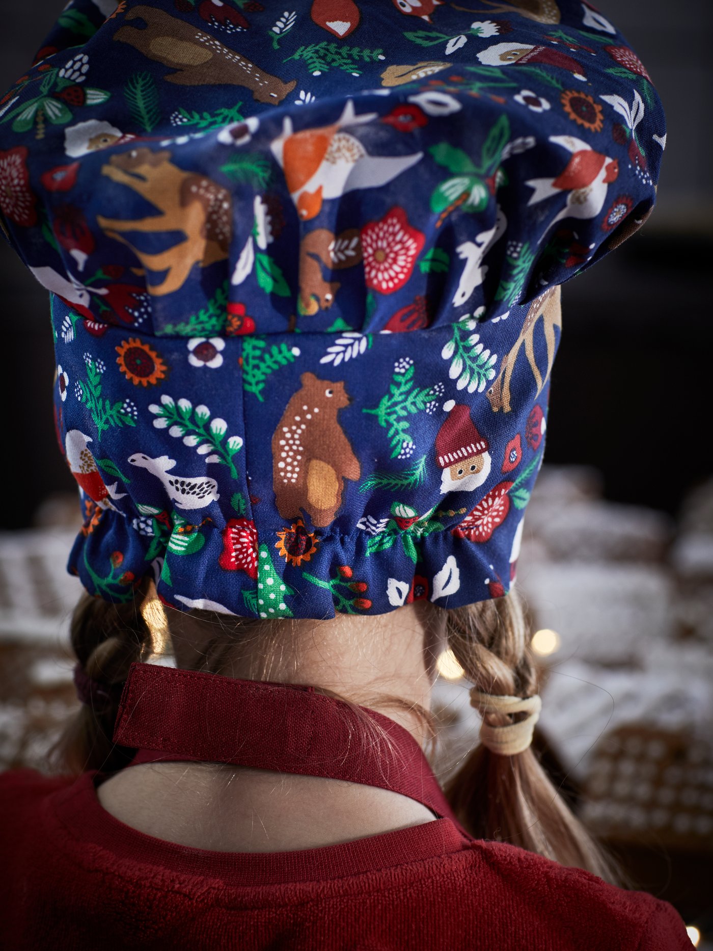 Young girl mixes batter wearing matching chef’s hat and IKEA holiday apron.