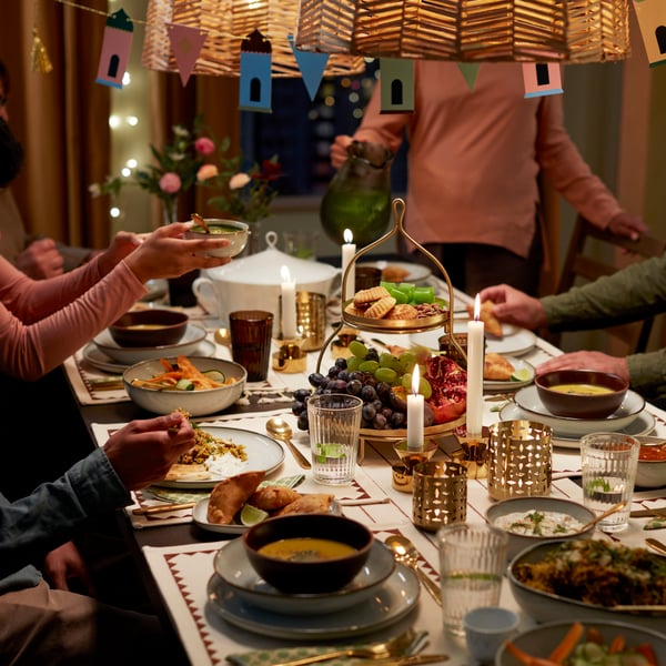 Various items from the GOKVÄLLÅ collection are shown on a festive dining table with people enjoying food.