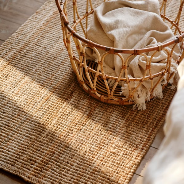 A natural LOHALS rug, flatwoven in the bedroom
