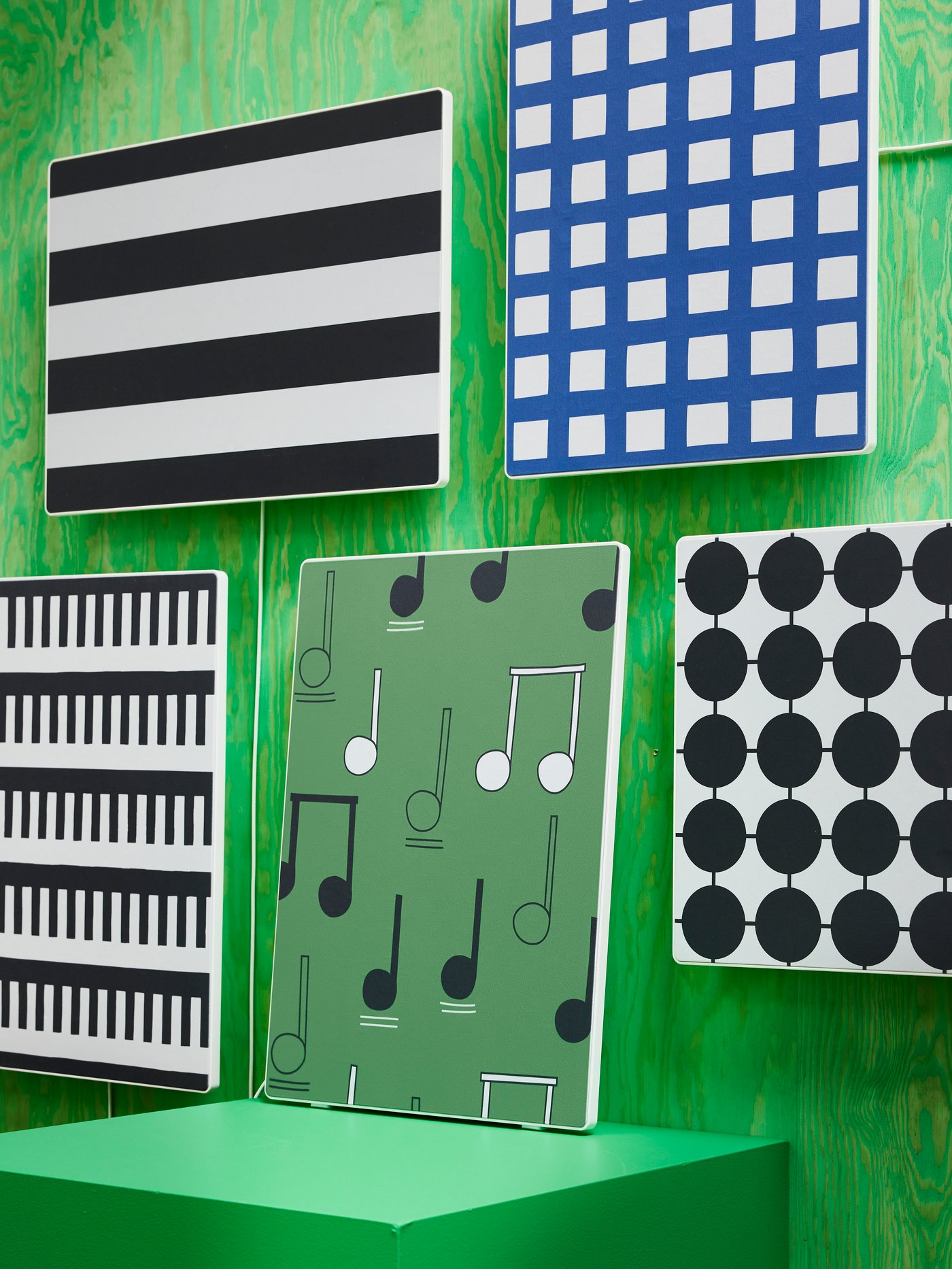 Four speakers mounted on a green wall. One is placed on a pedestal. All with SYMFONISK panel for picture frame speaker.