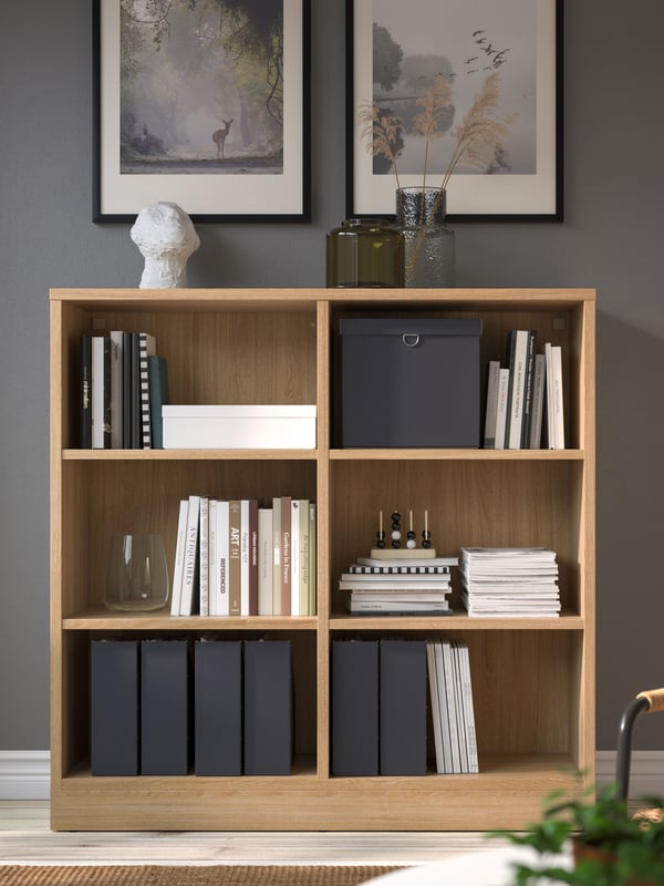 An IKEA TONSTAD bookcase in oak in a room with grey walls.