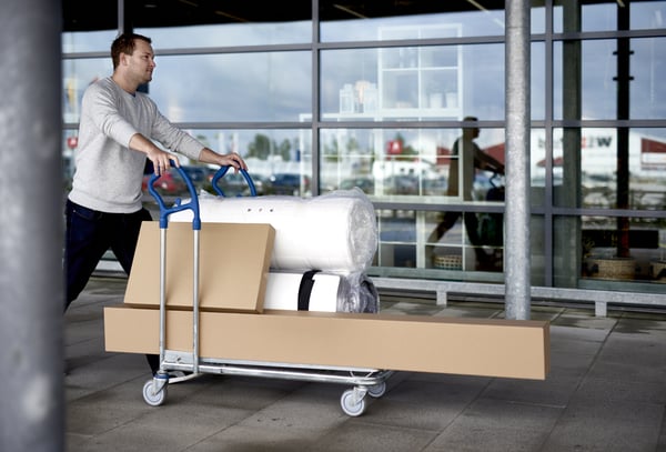 A man carrying furniture boxes on a trolley.