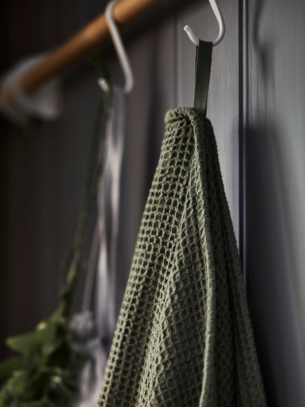 A light green VALLASÅN bath towel hangs from a white NEREBY s-hook hanging from a birch NEREBY rail.