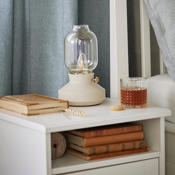 Une lampe de table TARNABY et un verre à whisky FRASERA sont placés sur le dessus d’une armoire-penderie SONGESAND.