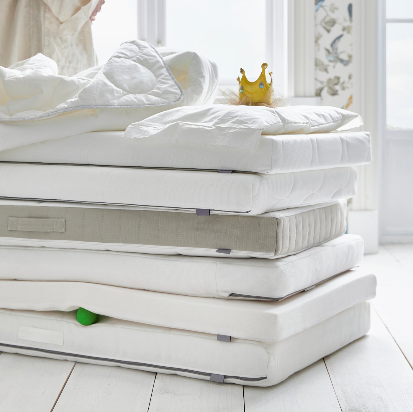 A pile of cot mattresses including PELLEPLUTT, SKÖNAST and KRUMMELUR foam mattresses and a DRÖMMANDE pocket sprung mattress.
