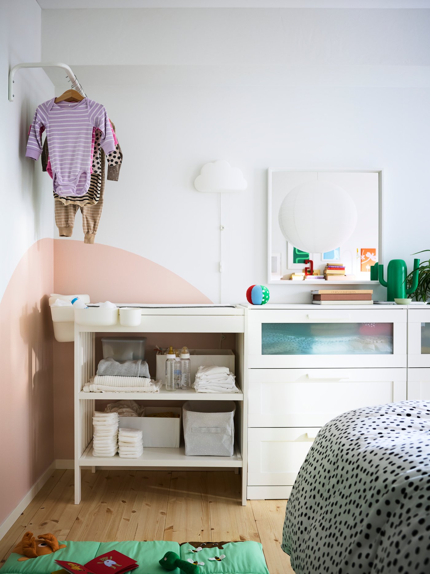 GULLIVER changing table next to BRIMNES chest of drawers, with some baby clothes hanging on a MULIG clothes bar above.