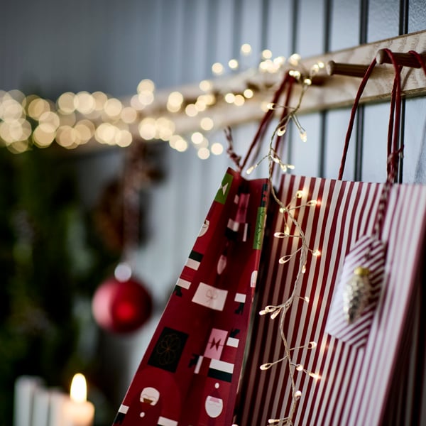 A mixed patterns red VINTERFINT gift bag and STRÅLA lighting chains. 