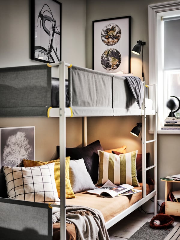 A white/light grey VITVAL bunk bed with seven cushions in various earth colour covers and a GUNNEMOR throw on the lower bed.
