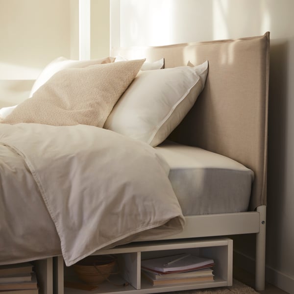 A KLEPPSTAD bed with white ÄNGSLILJA bed linen and two white FREDVANG underbed storage/bedside tables underneath it.