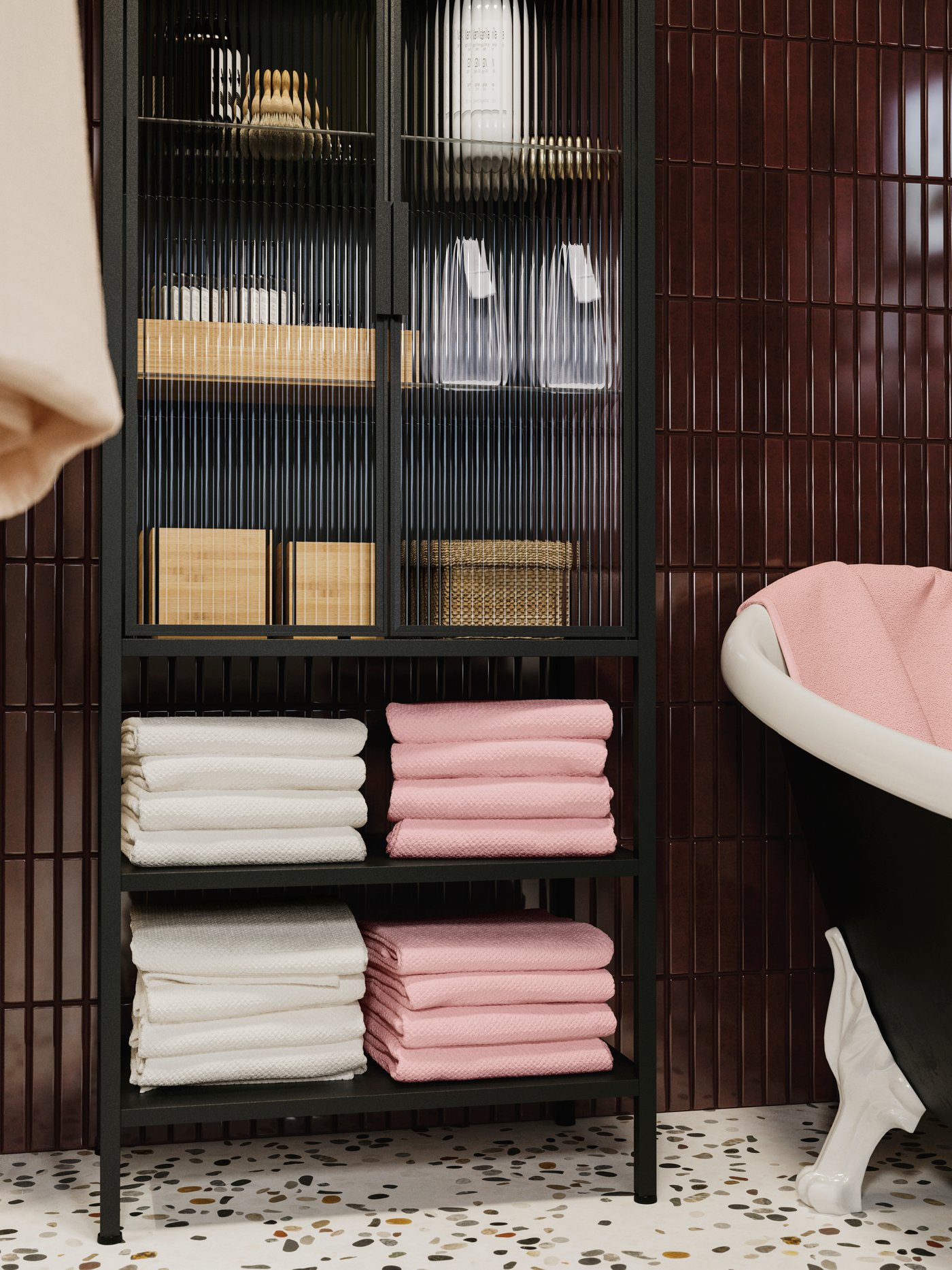 A MOSSJÖN glass-drawer cabinet with 2 doors, filled with white and pink towels and storage boxes, next to a bathtub.
