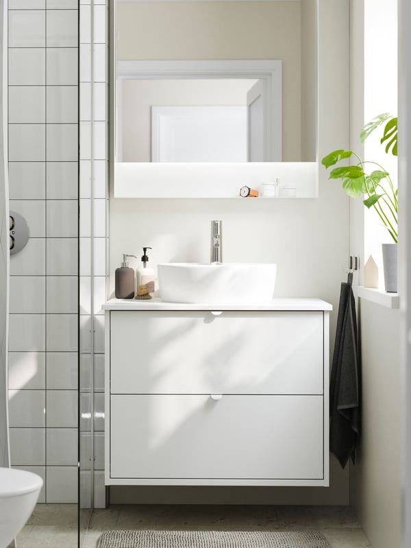A bright bathroom has a shower, a HAVBÄCK vanity with drawers, a TÖRNVIKEN countertop sink and a FAXÄLVEN mirror.