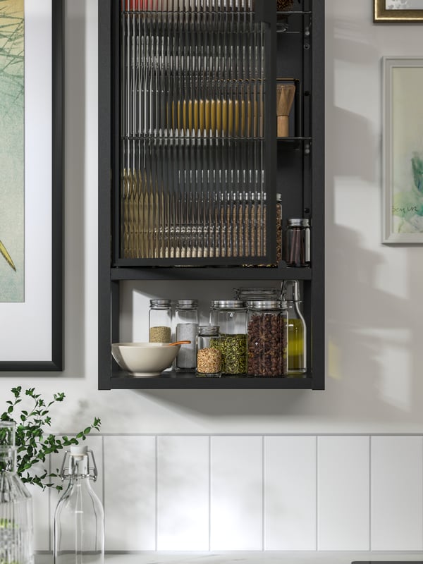 An anthracite-colour MOSSJÖN wall cabinet with shelves/glass door has spice jars inside and is mounted on a white wall.