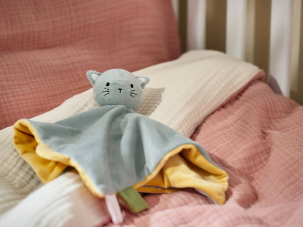 Une couverture douillette GULDVÄVARE bleue et jaune avec un doudou.
