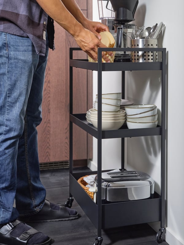 Kotak VARIERA berisi rempah dan botol di atas meja dapur berwarna hitam.