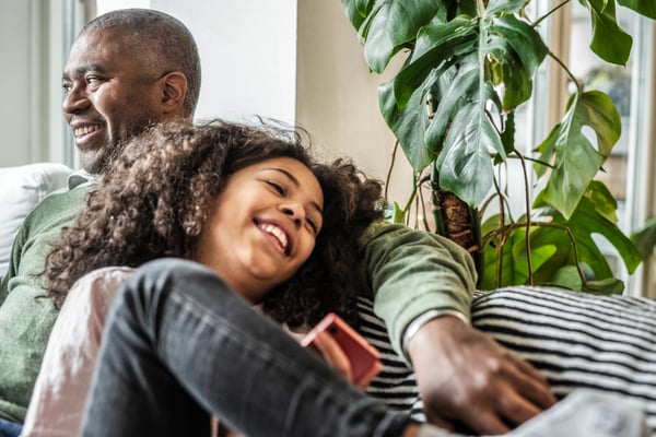 Father and daughter comfortably seated on a couch 