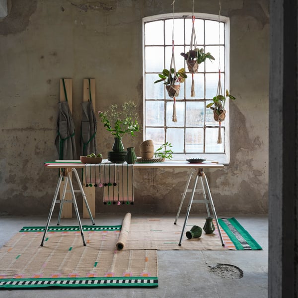 Parts of the MÄVINN collection are displayed on a table and hanging in front of a window in a room with an industrial look.
