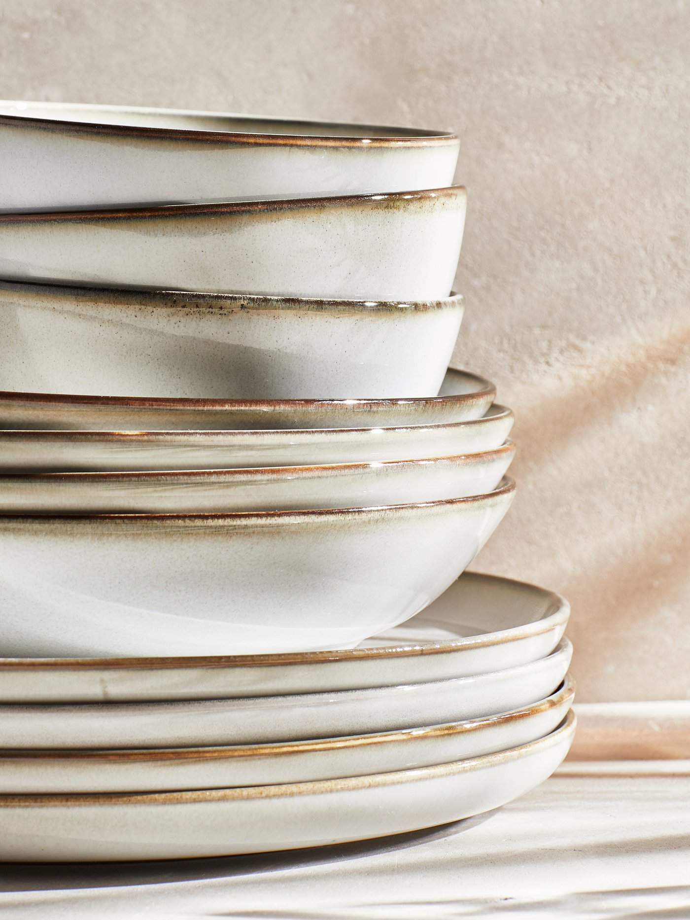 A pile of GLADELIG grey plates, deep plates and bowls stacked on top of each other.