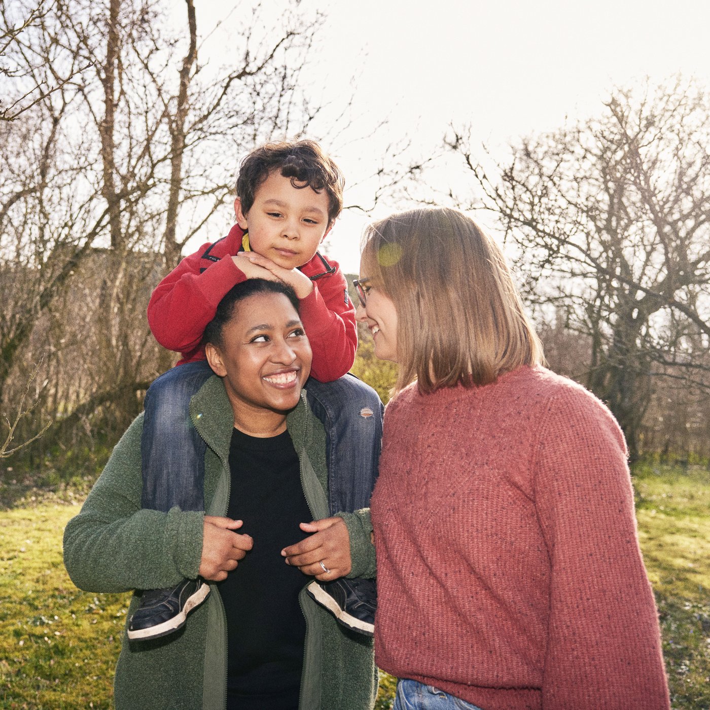 Alle en haar vrouw staan buiten in de tuin. Hun zoontje zit op haar schouders.