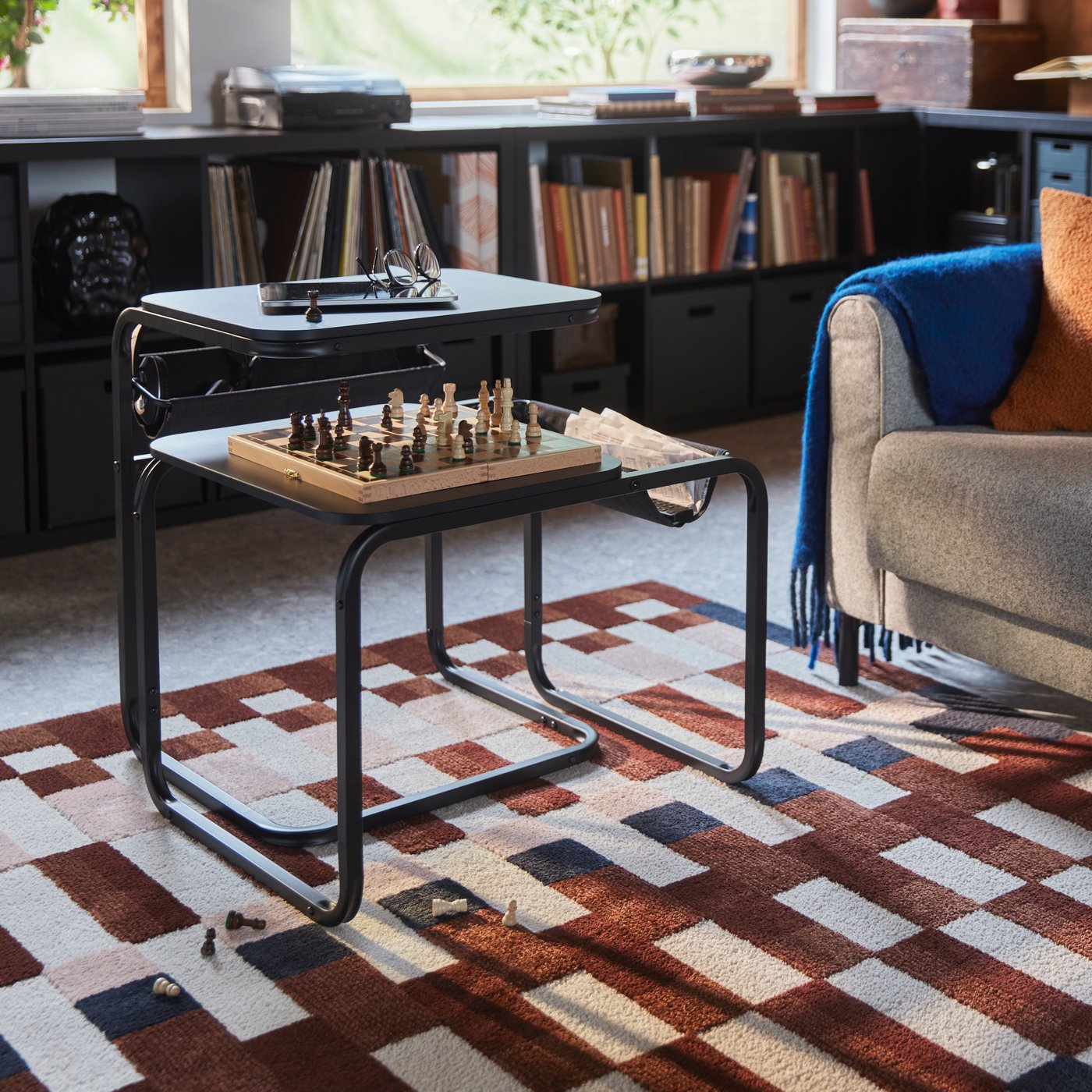 A living room with a chess game on an OLSERÖD side table beside a sofa and on a patterned MARKBLÅMME low pile rug.