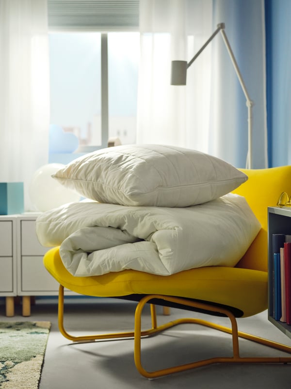 RUMSMALVA ergonomski jastuk na vrhu SMÅSPORRE jorgana za sva godišnja doba na SOTENÄS fotelji u blizini NYMÅNE podne/čitaće lampe.