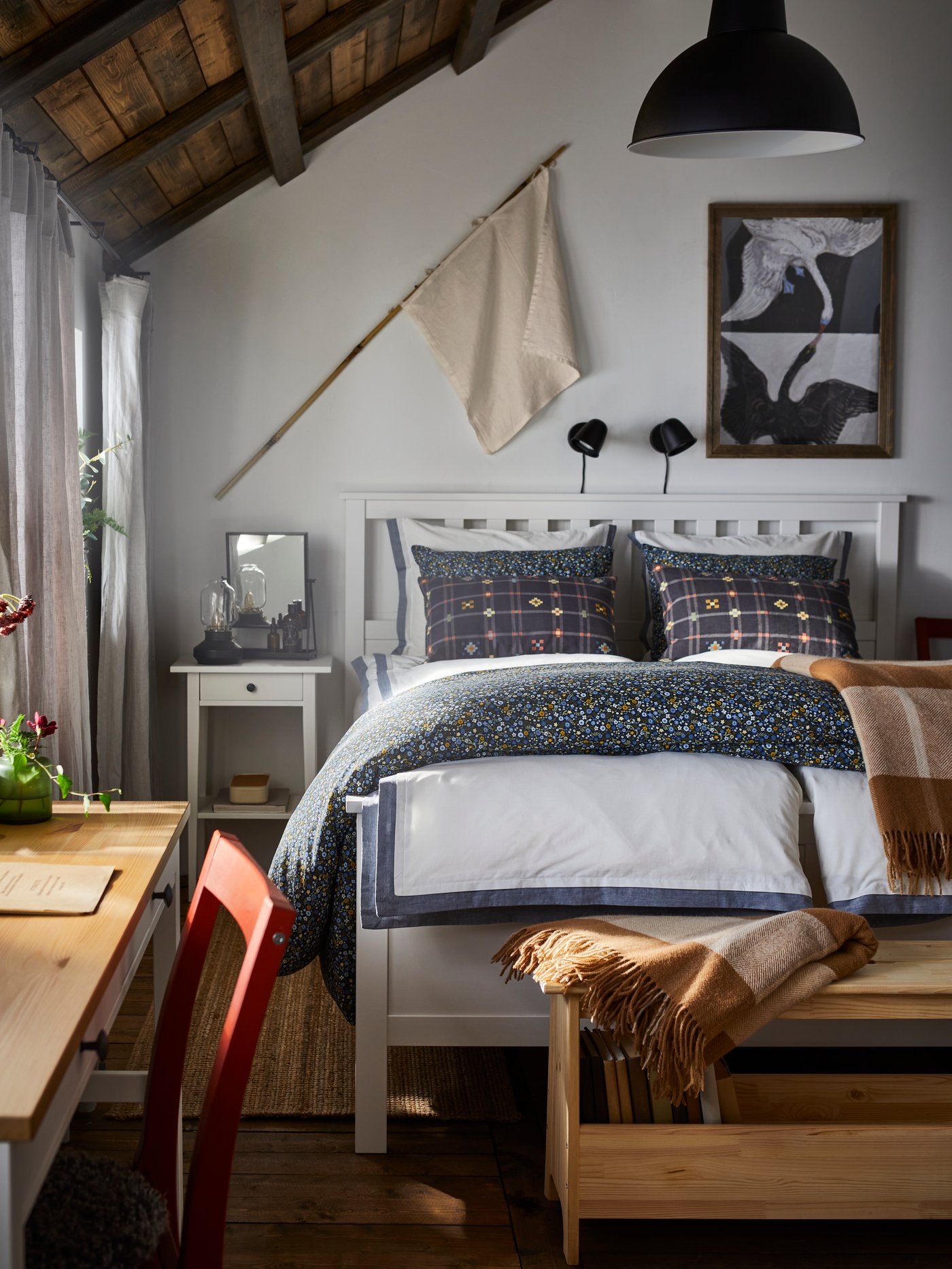 A HEMNES bed with white/blue TÅTELSMYGARE bed linen and two cushions with KUSTGRAN cushion covers stands in a bedroom.