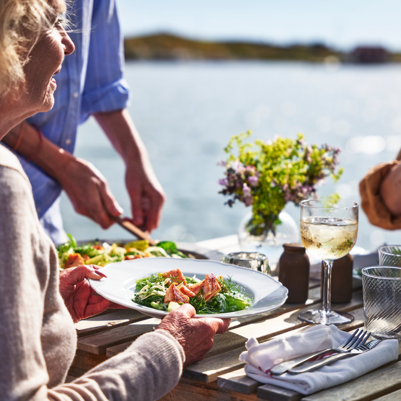 Une famille assise au bord de l’eau partageant un repas