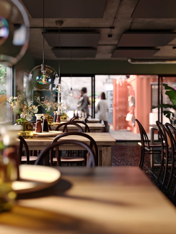 Rustični restoran smešten unutar kontejnera, s drvenim stolovima i stolicama, i JAKOBSBYN abažurima visilica iznad svakog stola.