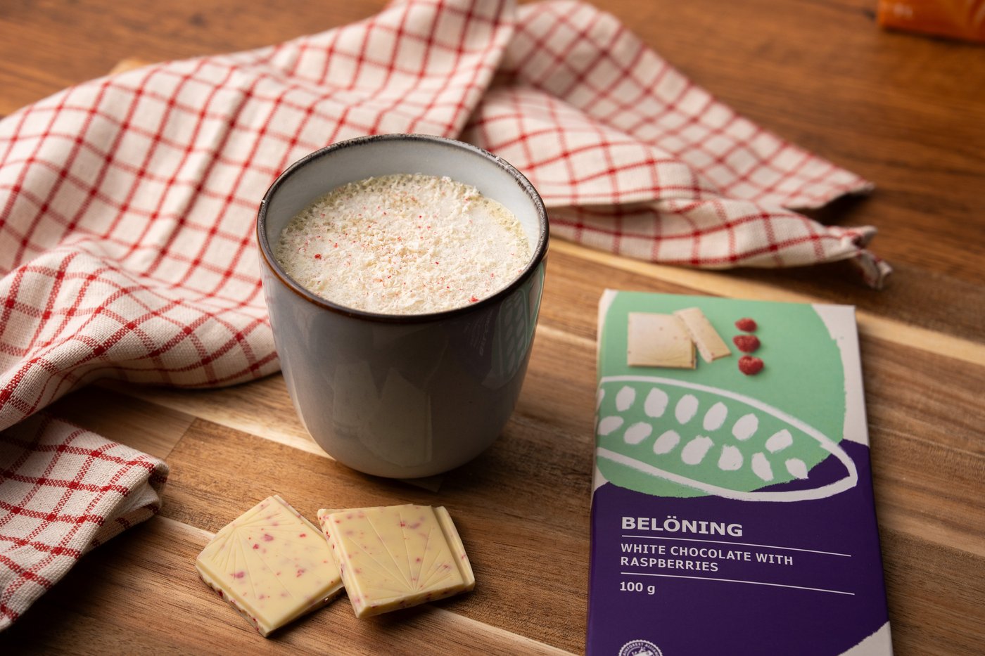 Preiselbeer White Chocolate Mocha in einer Tasse und einer weißen Schokolade, die daneben liegt.