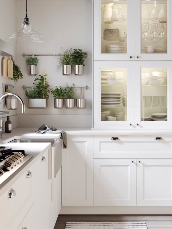 An AXSTAD kitchen with white base drawers, a white worktop and white cabinets with glass doors and integrated lighting.