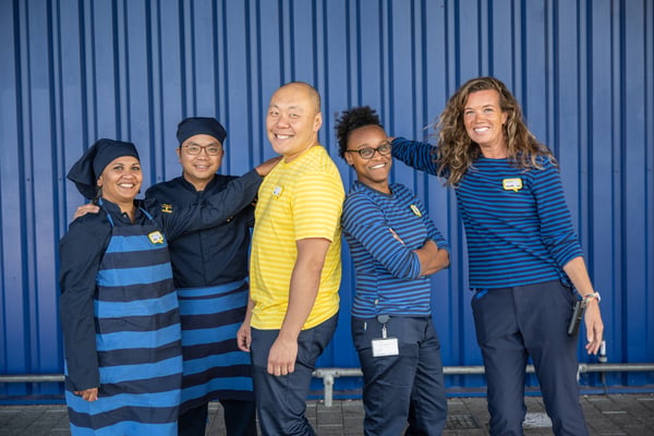A group of IKEA coworkers in uniform are posing for a photo.