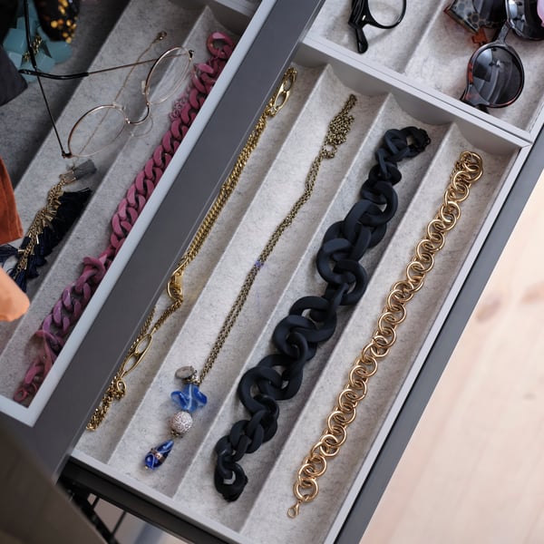 Grey KOMPLEMENT internal fitting pull-out tray in PAX wardrobe with grey frames showing felt internal trays with accessories neatly organised. 