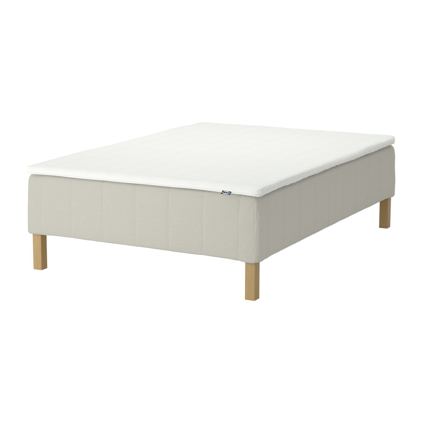 A beige RÅHOLMAR spring base bed with a mattress topper on top.