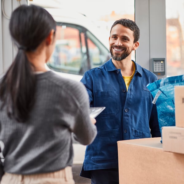 A customer receiving IKEA flatpacks from a smiling courier driver.