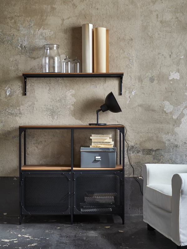 A black FJÄLLBO wall shelf mounted above a FJÄLLBO black shleving unit in a living room.
