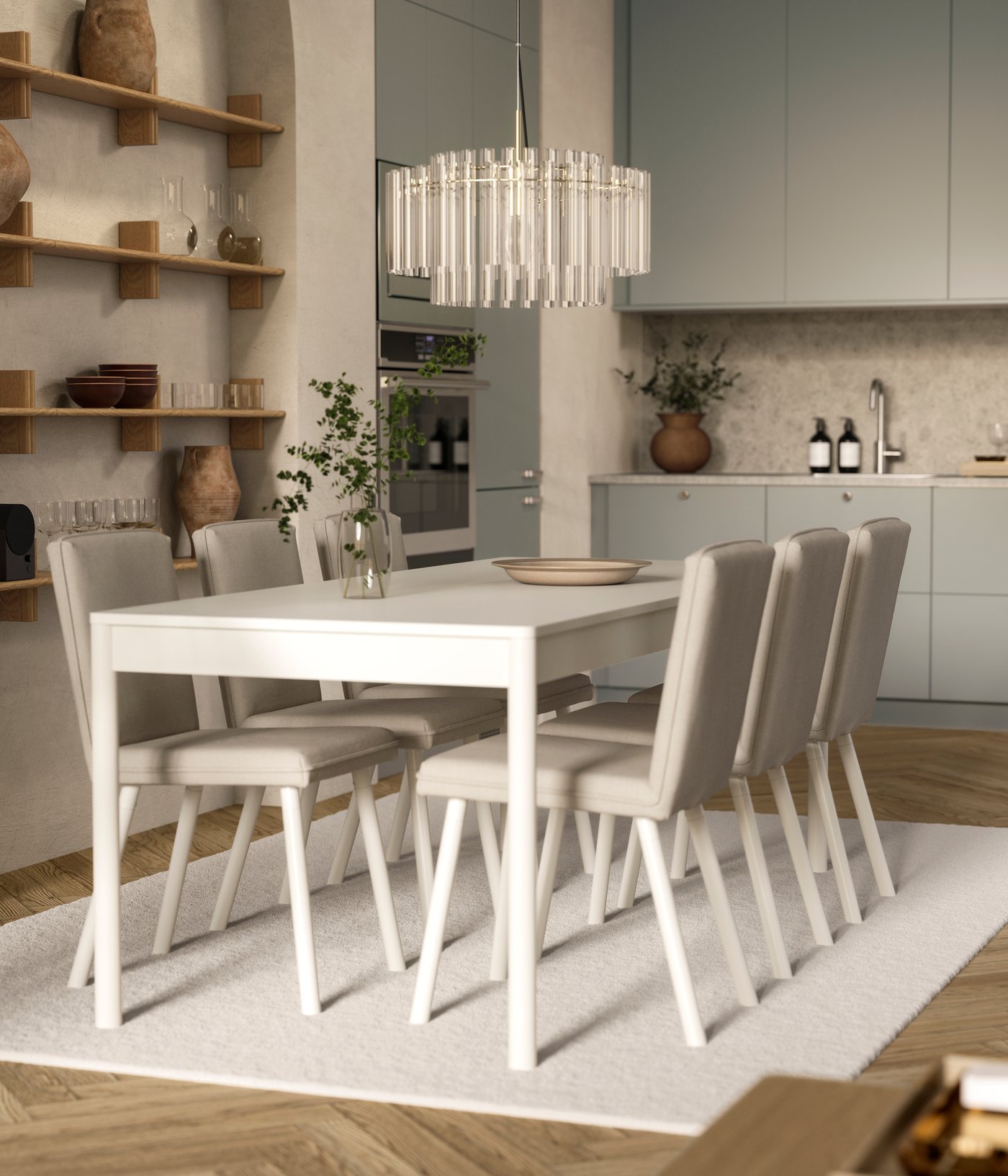 An off-white TONSTAD table with six chairs is on a rug and below a glass chandelier, by an open kitchen with modern fronts.