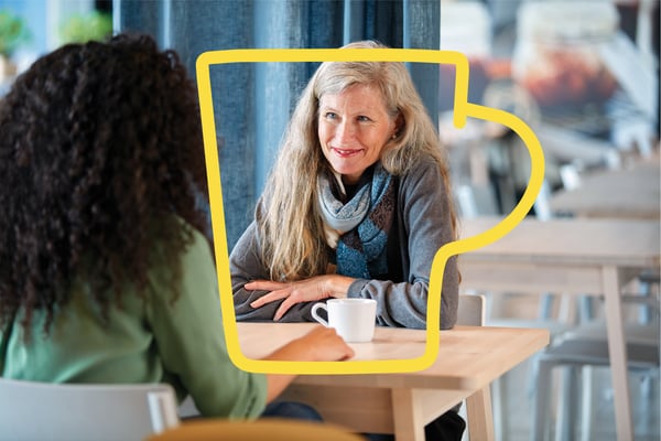 Nasmejana žena dugačke kose uživa u kafi u IKEA Švedskom restoranu sa ženom duge kovrdžave kose.