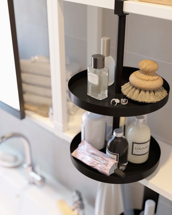 An ENHET swivel shelf in anthracite is attached to a white ENHET wall frame, and it has bathroom products stored on it.