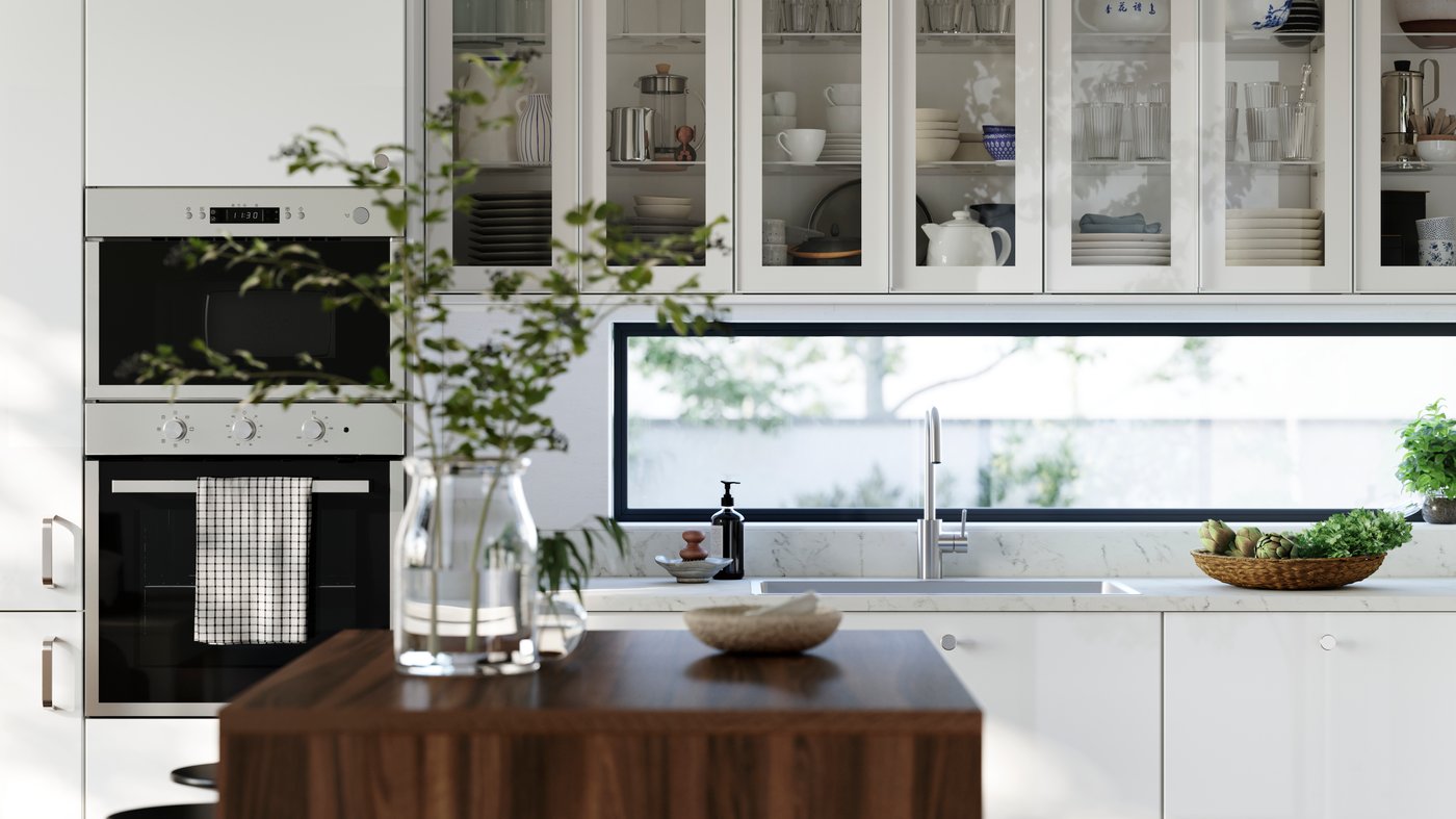 A kitchen with high-gloss RINGHULT fronts and wall cabinets with HEJSTA glass doors has a kitchen island in the foreground.