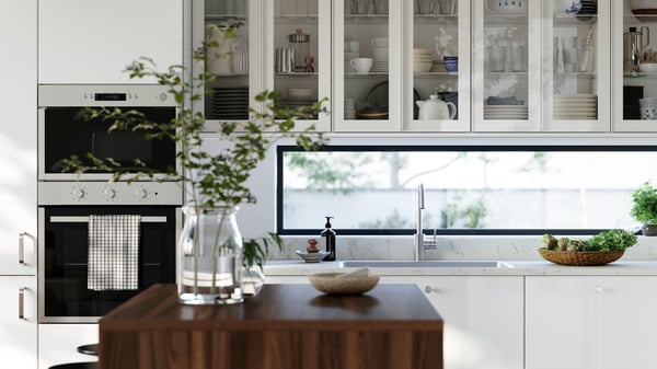 A kitchen with high-gloss RINGHULT fronts and wall cabinets with HEJSTA glass doors has a kitchen island in the foreground.