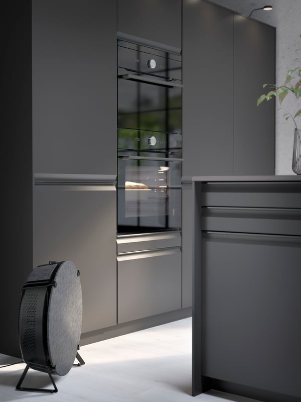 A kitchen with UPPLÖV doors and drawer fronts in anthracite, a STARKVIND smart air purifier in black and kitchen appliances.