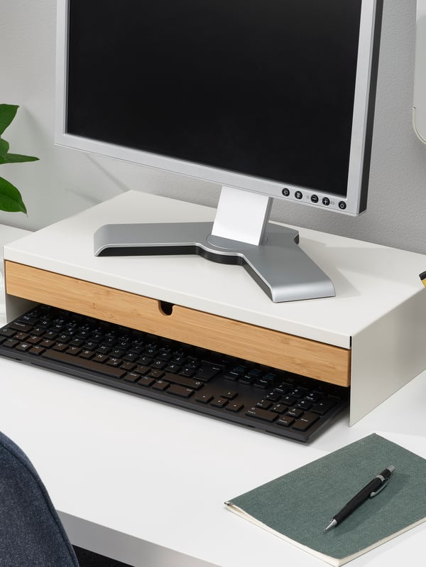 Es ist ein Monitorständer mit Schublade zu sehen, auf dem sich ein Bildschirm befindet.
