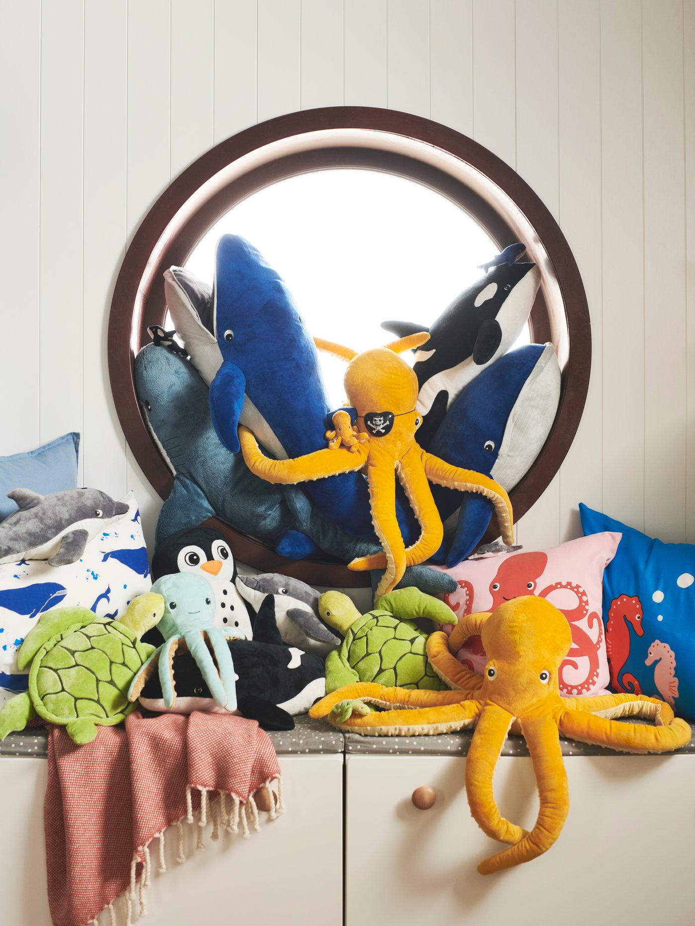 On a cabinet are ocean-inspired BLÅVINGAD soft toys that are made from a mix of recycled PET and ocean-bound plastic.