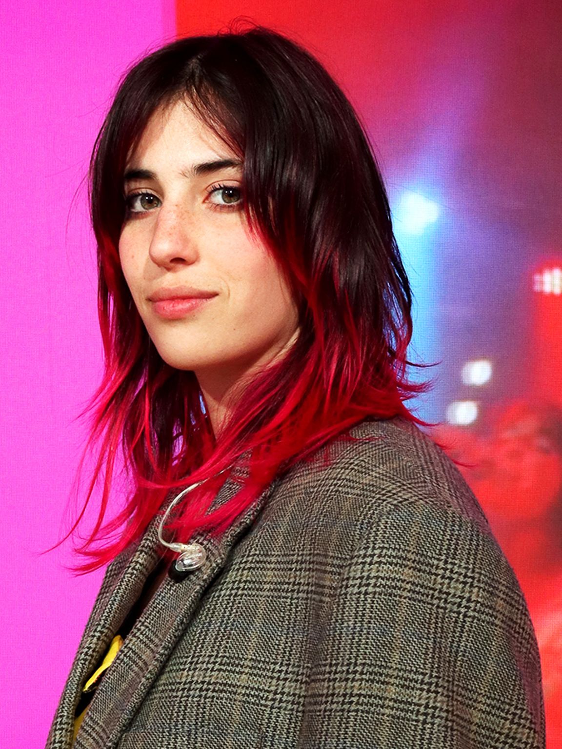 Chiamamifaro staat op een podium met op de achtergrond een zacht roze afkomstig van de digitale display die tijdens de designweek in Milaan editie 2024 werd gebruikt in het IKEA paviljoen. 