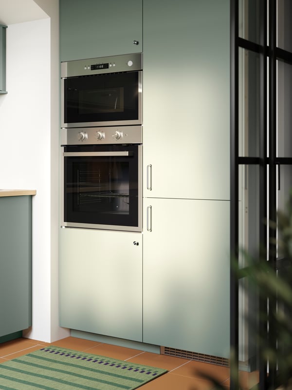 A kitchen with NICKEBO fronts in matt grey-green with integrated fridge/freezer, a built-in oven and microwave oven.