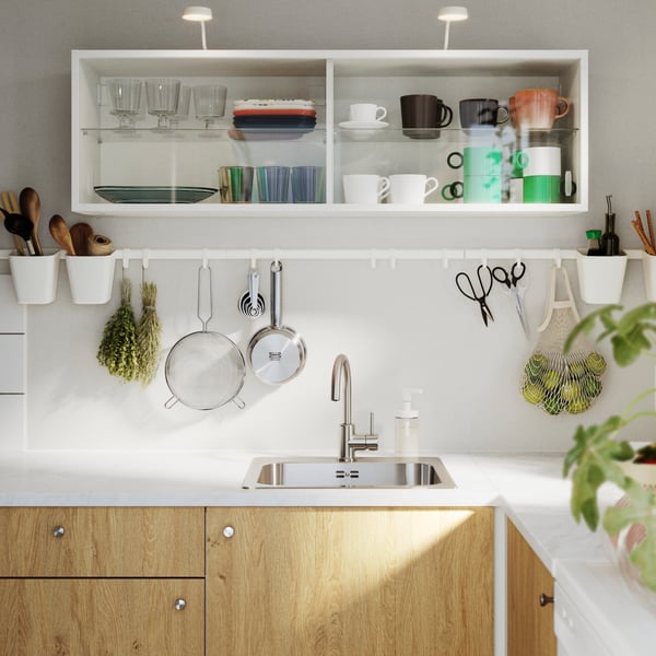 A white SUNNERSTA rail with four hooks and two containers displays cups and utensils in a modern kitchen.
