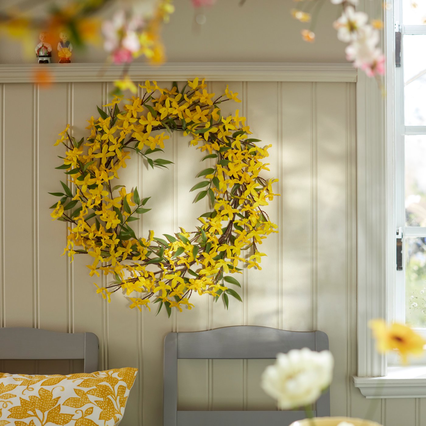 An in/outdoor/forsythia yellow SMYCKA artificial wreath at the wall.