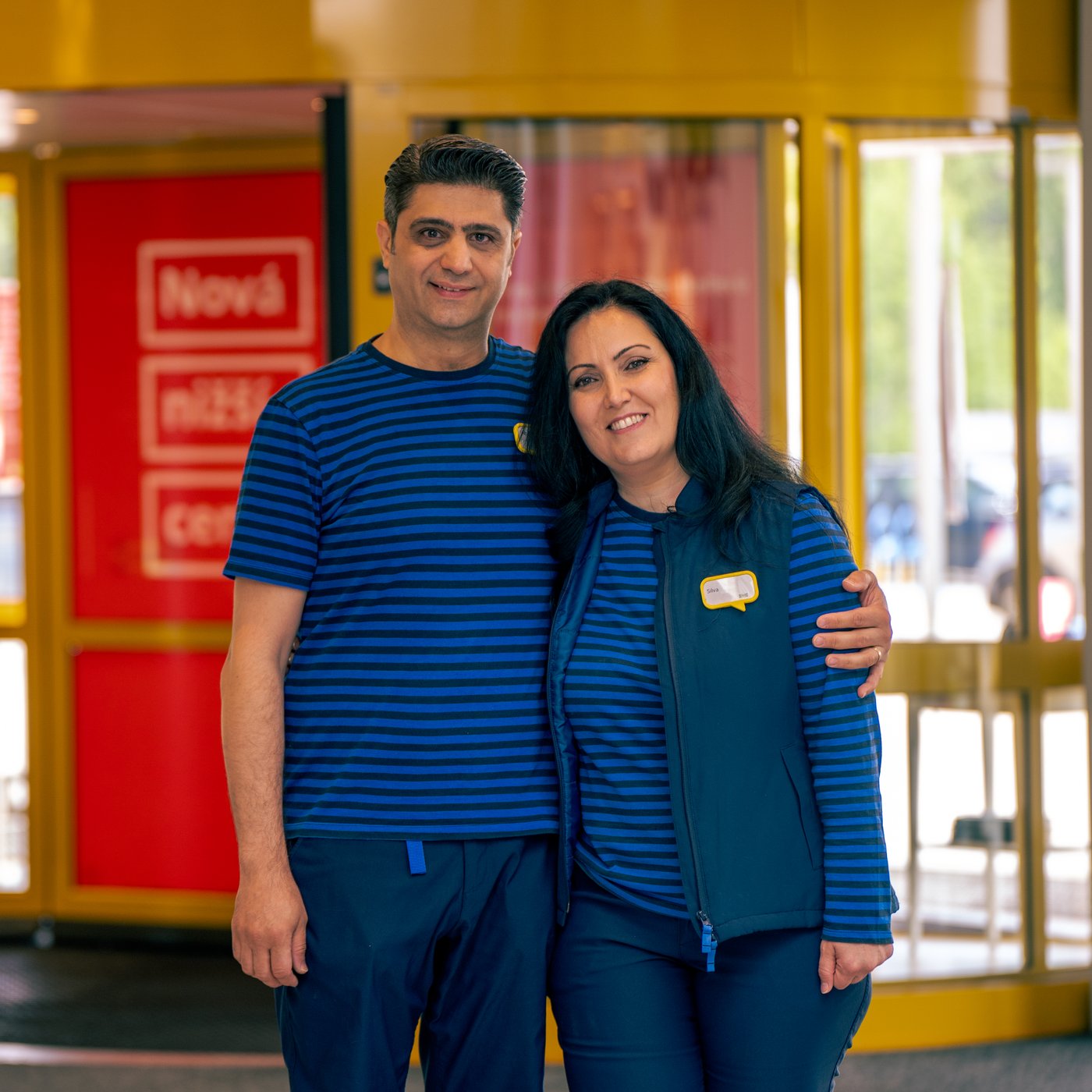 Zagrljeni Silva i Abdul u plavim IKEA radnim uniformama.