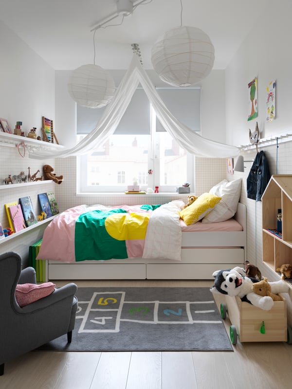 Una habitación de niños con una cama SLÄKT y al costado de la cama un tapete infantil HEMMAHOS.