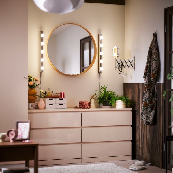 Deux commodes 3 tiroirs MALM orange clair côte à côte dans le coin d’une chambre, surmontées d’un miroir rond et d’éclairages.