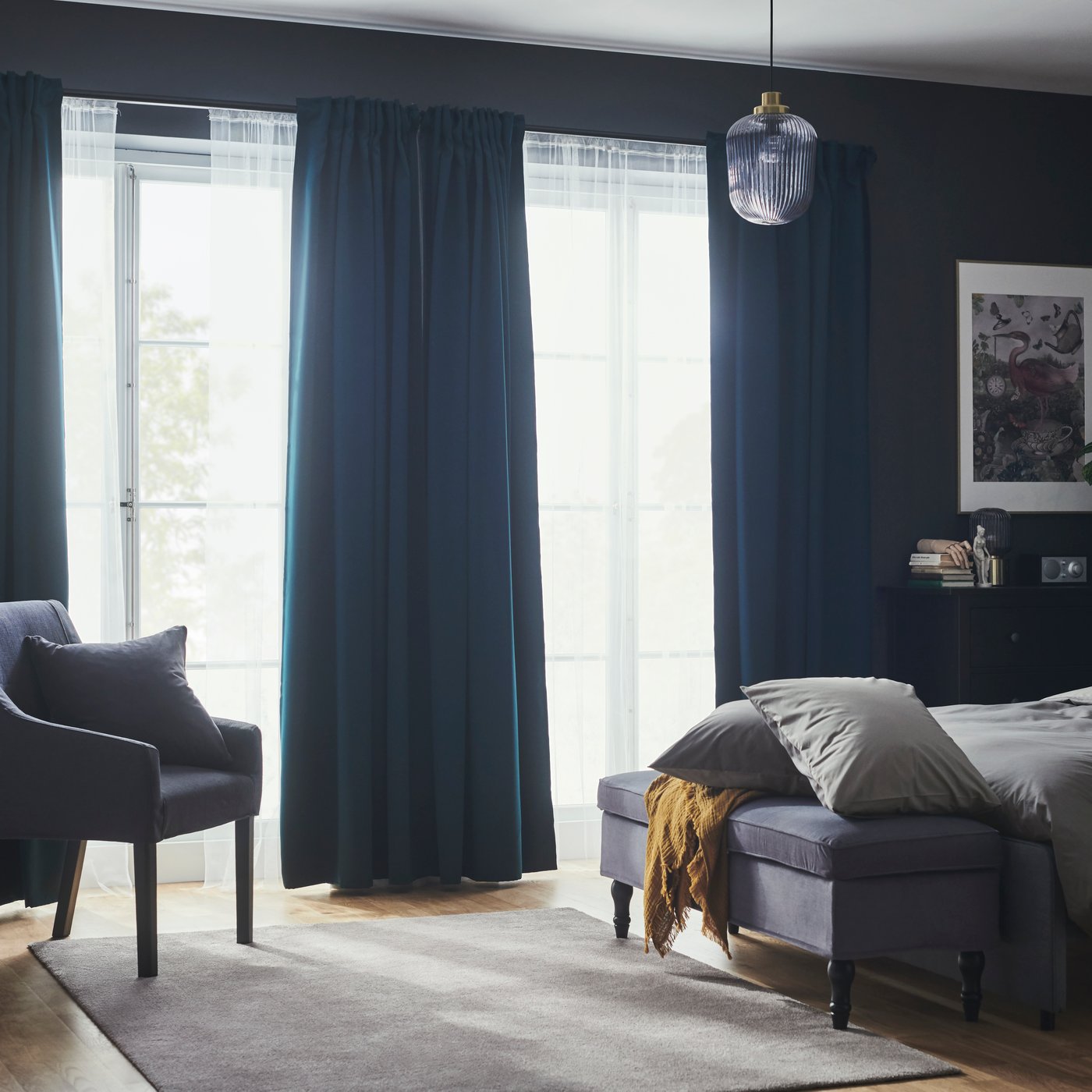 Chambre à coucher avec rideaux occultants MAJGULL turquoise foncé et voilages habillant de grandes fenêtres près d’un lit et d’une banquette.